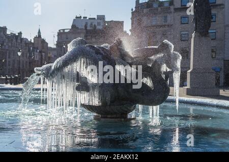 Statues de fontaine congelées de Trafalgar Square à Londres. Des glaçons qui pendent mystiquement de la fontaine d'eau en bronze Banque D'Images