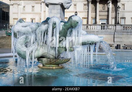 Statues de fontaine congelées de Trafalgar Square à Londres. Des glaçons qui pendent mystiquement de la fontaine d'eau en bronze Banque D'Images