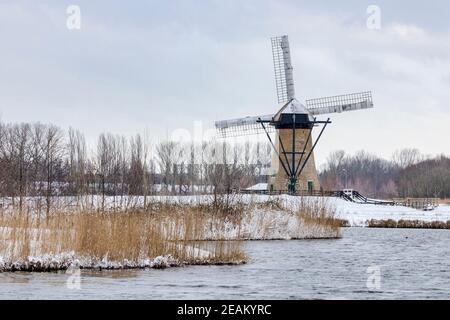 Moulin à vent hollandais historique de Pendrecht Rotterdam dans un paysage enneigé. Le premier plan montre les roseaux et l'eau. Banque D'Images