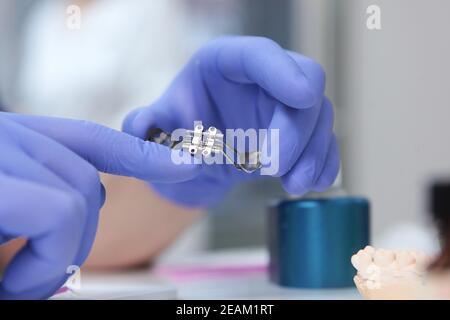 Le médecin tient les bretelles. Alignement de la dentition ou de la morsure. Personne méconnaissable. Mains dans des gants de protection. Photo macro. Banque D'Images