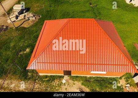 Maison avec un toit orange en métal, vue d'en haut. Profil métallique ondulé peint sur le toit. Banque D'Images