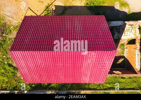 Une maison avec un toit rouge faite de feuilles de métal ondulé. Toit de métal ondulé profil. Metal 600x600. Banque D'Images