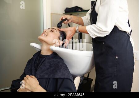 Coiffeur lave les cheveux de la femme, salon de coiffure Banque D'Images