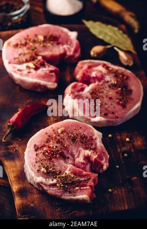 Steaks de longe de porc aux épices moulues sur la planche à découper Banque D'Images