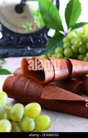 Pastilla de raisins. Produit naturel sans conservateurs. Nourriture pour végétariens. Grappes de raisins sur fond clair. Échelles vintage en arrière-plan. Banque D'Images