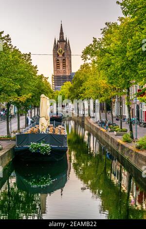 Vue au coucher du soleil sur l'église Oude Kerk derrière un canal à Delft, pays-Bas Banque D'Images