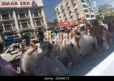 Les manifestants portant des robes de mariée marchent dans les rues et tiennent des pancartes pendant la manifestation. Des milliers de personnes sont descendues dans les rues de Yangon le cinquième jour des manifestations contre le coup d'État militaire et ont demandé la libération d'Aung San Suu Kyi. L'armée du Myanmar a détenu le conseiller d'État du Myanmar, Aung San Suu Kyi, le 01 février 2021 et a déclaré l'état d'urgence tout en prenant le pouvoir dans le pays pendant un an après avoir perdu les élections contre la Ligue nationale pour la démocratie (NLD). Banque D'Images