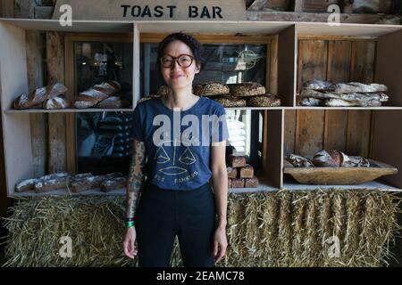 GRANDE-BRETAGNE / Angleterre / Hertfordshire /Woman avec t-shirt ' plus boulangers moins banquiers debout devant pain artisanal . Banque D'Images