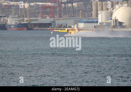 Un avion de lutte contre le feu collectant de l'eau de mer pour éteindre un feu de forêt. Banque D'Images