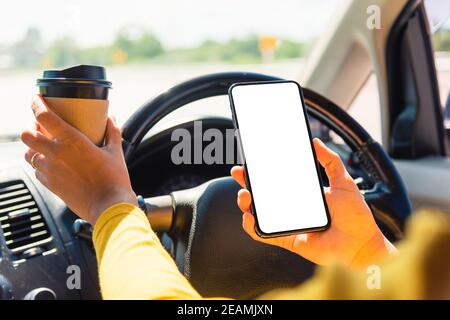 femme buvant un café chaud à emporter dans une voiture et à l'aide d'un smartphone Banque D'Images