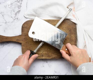 les mains des femmes tiennent un couteau de cuisine et un taille-crayon avec une poignée Banque D'Images