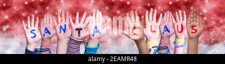 Les mains des enfants Mot de construction Santa Claus, fond rouge de Noël Banque D'Images