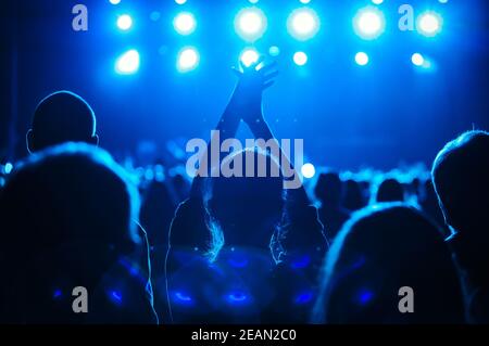 Silhouette de jeune femme heureuse faisant la fête lors d'un concert en direct Salle de musique surpeuplée. Grand groupe de jeunes sur la piste de danse en boîte de nuit Banque D'Images