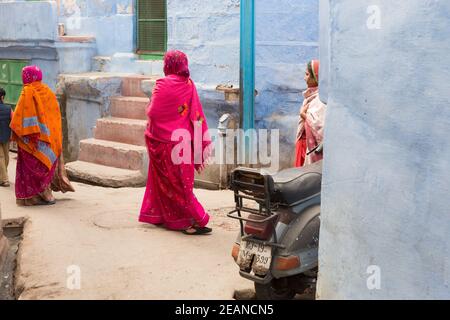 Jodhpur Inde les femmes dans la guirlande colorée passe par les maisons bleues traditionnelles Banque D'Images