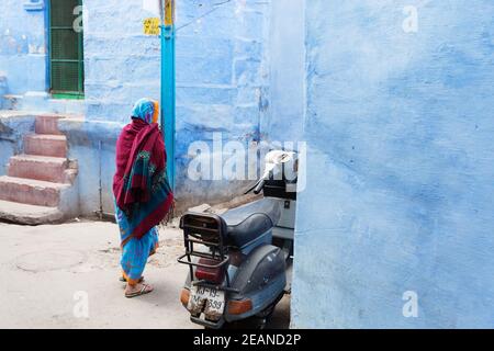 Jodhpur Inde femme dans la guirlande colorée passe par les maisons bleues traditionnelles Banque D'Images