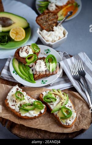 Sandwichs au fromage doux, à l'avocat et au concombre. Le petit déjeuner est sur la table. Une alimentation saine. Toasts et tartiner dessus. Sandwich avocat mortivie. Santé Banque D'Images