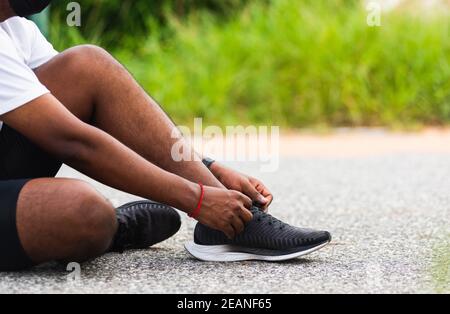 coureur noir homme assis cordonnet essayer les chaussures de course à pied Banque D'Images