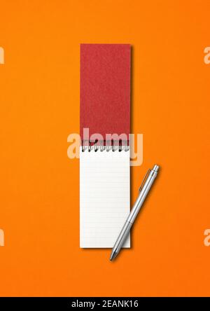 Bloc-notes et stylo à spirale ouverts vierges isolés sur l'orange Banque D'Images
