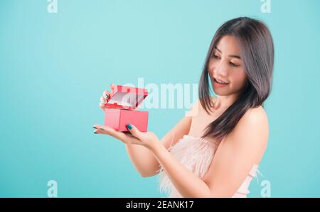 femme debout sourire ouvrant une boîte cadeau rouge, surprise anniversaire Banque D'Images