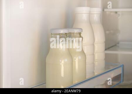 Yaourt dans des bouteilles en verre et en plastique blanc sur l'étagère du réfrigérateur vide ouvert. Concept d'alimentation saine. Aliments fermentés. Banque D'Images