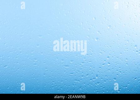 Gouttes de pluie sur la fenêtre en verre sur le ciel gris et bleu Banque D'Images