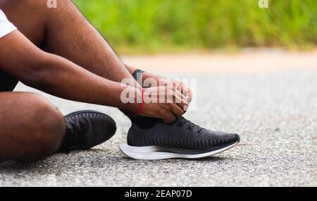 coureur noir homme assis cordonnet essayer les chaussures de course à pied Banque D'Images