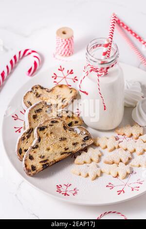 Bouteille de lait avec une boisson de Noël traditionnelle, petits biscuits et canne à sucre sur fond blanc. Banque D'Images