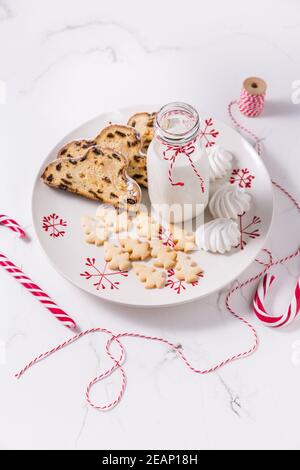 Bouteille de lait avec une boisson de Noël traditionnelle, petits biscuits et canne à sucre sur fond blanc. Banque D'Images