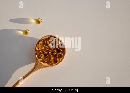 Capsules de vitamine D dans une cuillère en bois Banque D'Images