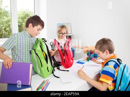 Les enfants avec des sacs à dos assis sur l'escalier près de l'école Banque D'Images