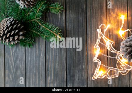 Branches d'arbres de Noël, cônes de pin et guirlandes illuminées sur fond de bois foncé, vue de dessus avec espace pour les copies Banque D'Images