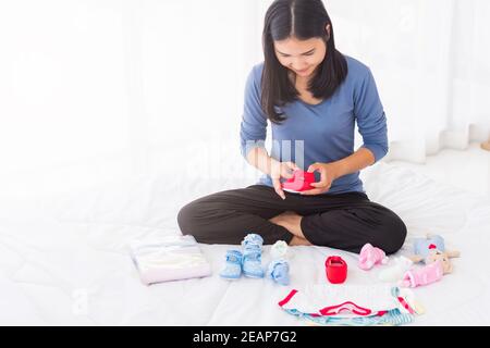 mère préparant des vêtements de bébé se reposant et se reposant sur le lit Banque D'Images