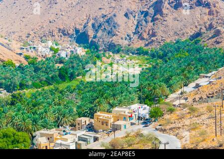 Vue aérienne d'un village entouré d'une forêt de palmiers dans le Wadi Tiwi en Oman. Banque D'Images