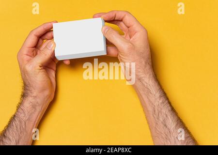 Un homme ouvre les mains d'une boîte devant le jaune maquette d'arrière-plan série 290 Banque D'Images