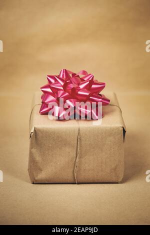 Boîte cadeau en papier brun Uni avec décoration d'emballage rose sur fond marron, concept de présent et d'anniversaire, design rétro Banque D'Images