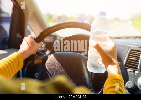 femme tenant une bouteille d'eau pour boire tout en conduisant le voiture Banque D'Images