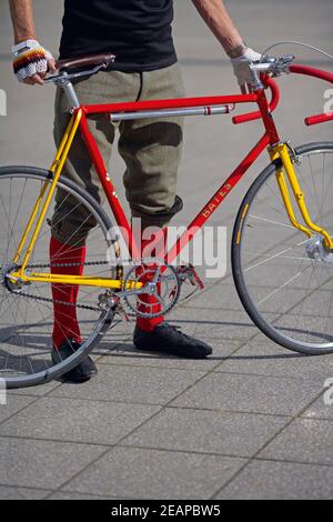 homme portant un pantalon plus farines pose avec un vélo rétro Banque D'Images