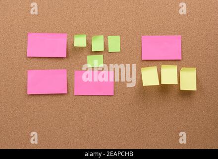 les bâtons multicolores sont collés au panneau de liège brun Banque D'Images