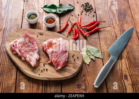 Steaks crus aux épices et couteau sur table en bois. Banque D'Images