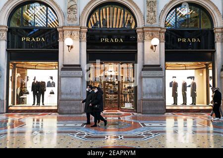 Couple marchant en face de Prada boutique dans la galerie Vittorio Emanuele II dans le centre de Milan, Italie. Les gens portent des masques chirurgicaux Banque D'Images