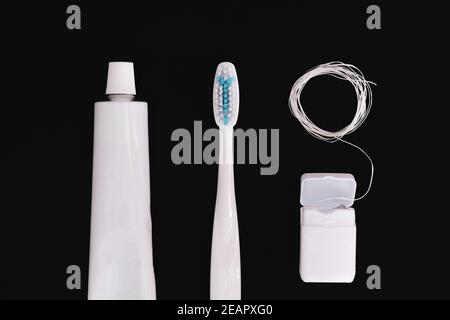 Objets d'hygiène dentaire : brosse à dents, dentifrice et soie dentaire. Accessoires génériques blancs pour garder les dents en santé sur fond noir Banque D'Images