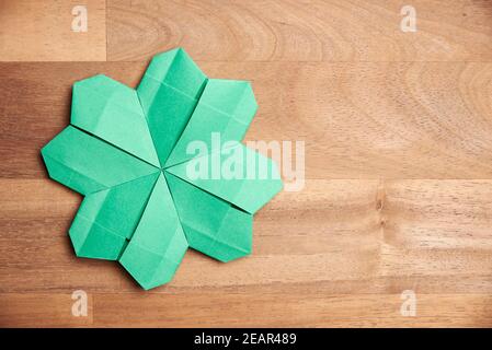 Trèfle à quatre feuilles d'origami, en papier vert, sur fond de bois. Concepts de chance et de la Saint-Patrick. Image avec espace de copie. Banque D'Images