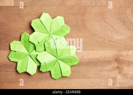 Trèfle à quatre feuilles d'origami, en papier vert clair, sur fond de bois. Concepts de chance et de la Saint-Patrick. Image avec espace de copie. Banque D'Images