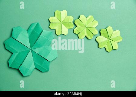 Trèfle à quatre feuilles d'origami, en papier vert, sur fond vert. Concepts de chance et de la Saint-Patrick. Image avec espace de copie. Banque D'Images