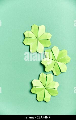 Trèfle à quatre feuilles d'origami, en papier vert clair, sur fond vert. Concepts de chance et de la Saint-Patrick. Image avec espace de copie. Banque D'Images