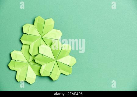 Trèfle à quatre feuilles d'origami, en papier vert clair, sur fond vert. Concepts de chance et de la Saint-Patrick. Image avec espace de copie. Banque D'Images