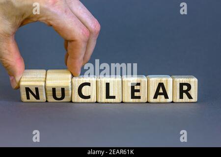 Symbole nucléaire ou clair. Homme d'affaires transforme un cube et transforme le mot « nucléaire » en « clair ». Magnifique fond gris. Nucléaire ou clair et affaires Banque D'Images