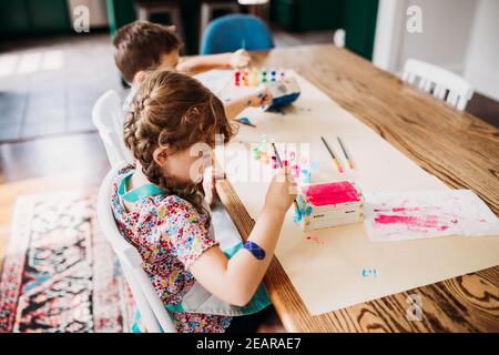 Les jeunes enfants font de l'art et de l'artisanat avec de la peinture de couleur arc-en-ciel Banque D'Images