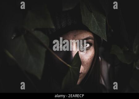 Portrait d'une fille de gingembre avec des feuilles de fougères couvrant la partie son visage Banque D'Images