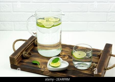 Une limonade faite maison en chaux se tient dans un verre et verseuse sur un plateau en bois Banque D'Images